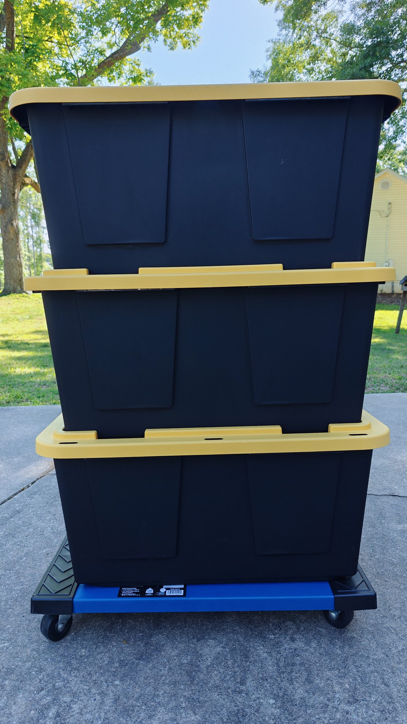 Three black and yellow Smart Fox totes stacked on a moving dolly outdoors